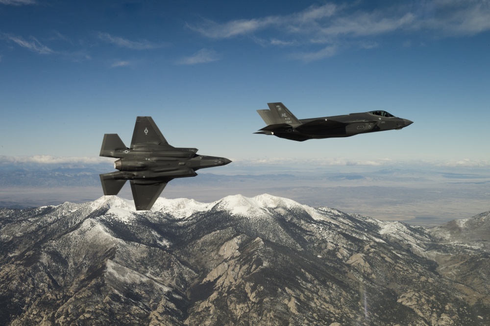 two fighter jets flying above mountains 