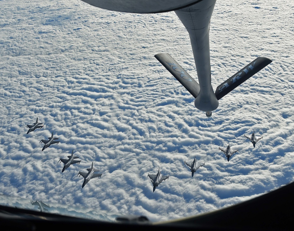 multiple fighter jets in formation over ocean about to be refueled