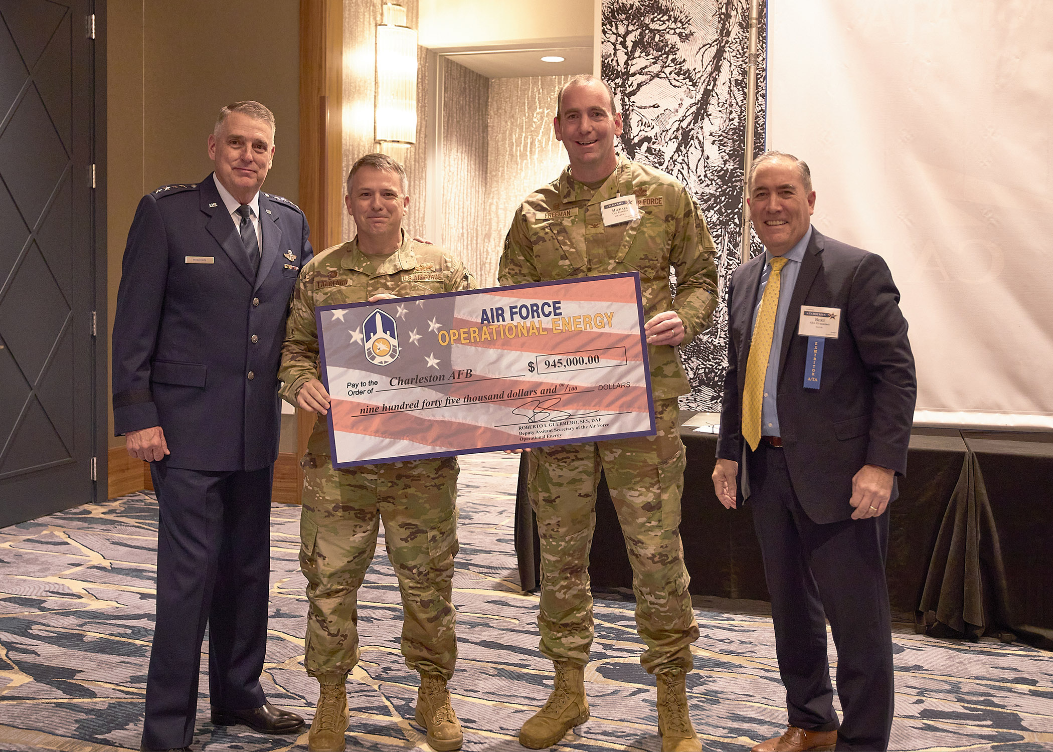 3 Airmen and 1 SES Civilian pose for photo with large check 